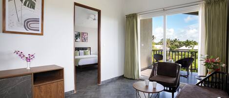 A hotel room with a balcony, a bed, a desk, and a chair.