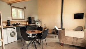 Eine kompakte Küche mit Waschmaschine, einem Esstisch mit Stühlen und einer Couch.