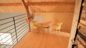 Eine Holzhütte mit einem Balkon, zwei gelben Stühlen und einem kleinen Tisch.