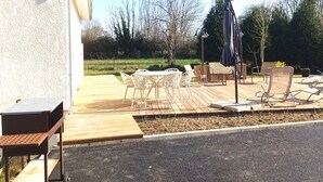 A patio area with outdoor furniture, a table, and a chair. - LA TRANQUILITE NORMANDE Country cottage surrounded by animals! (Livarot-Pays-d'Auge)