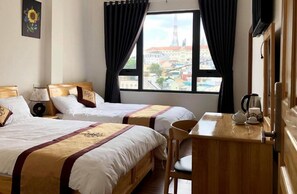 Une chambre d’hôtel avec deux lits, un bureau en bois, une chaise, une fenêtre avec des rideaux et une vue sur la ville.