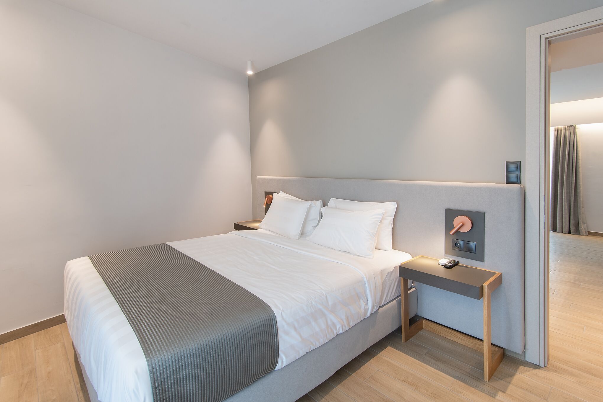 A modern bedroom with a bed, bedside table, and a nightstand.