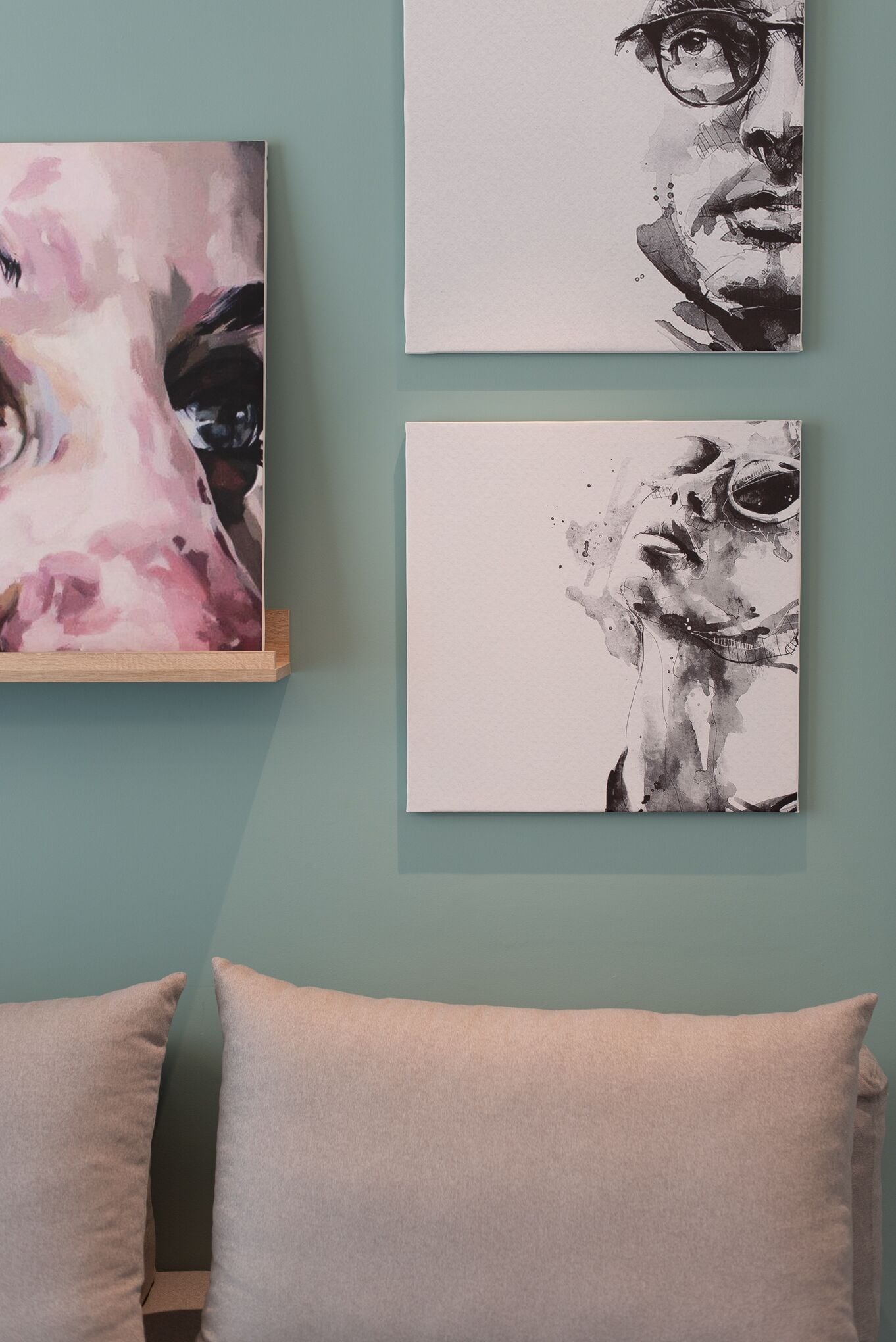 Une pièce avec un mur de couleur turquoise, un lit avec deux oreillers et trois œuvres d’art.
