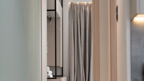 A hallway leading to a bathroom with a towel rack and a shower curtain. - The Residences Kalamata (Kalamata)