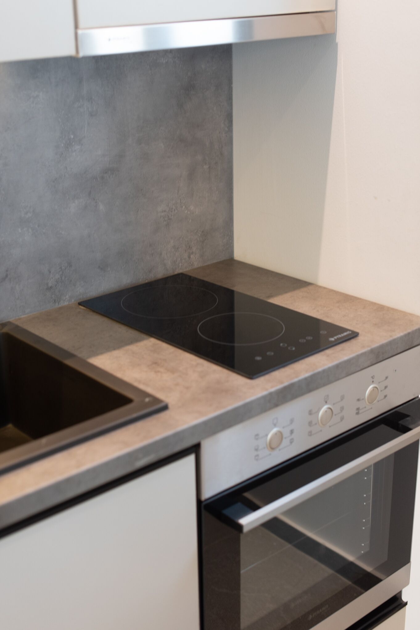 A kitchen with a built-in induction cooktop, a stainless steel oven, and a modern countertop.