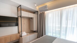 A modern hotel room with a bed, a built-in wardrobe, a seating area, and a large window with curtains. - The Residences Kalamata (Kalamata)