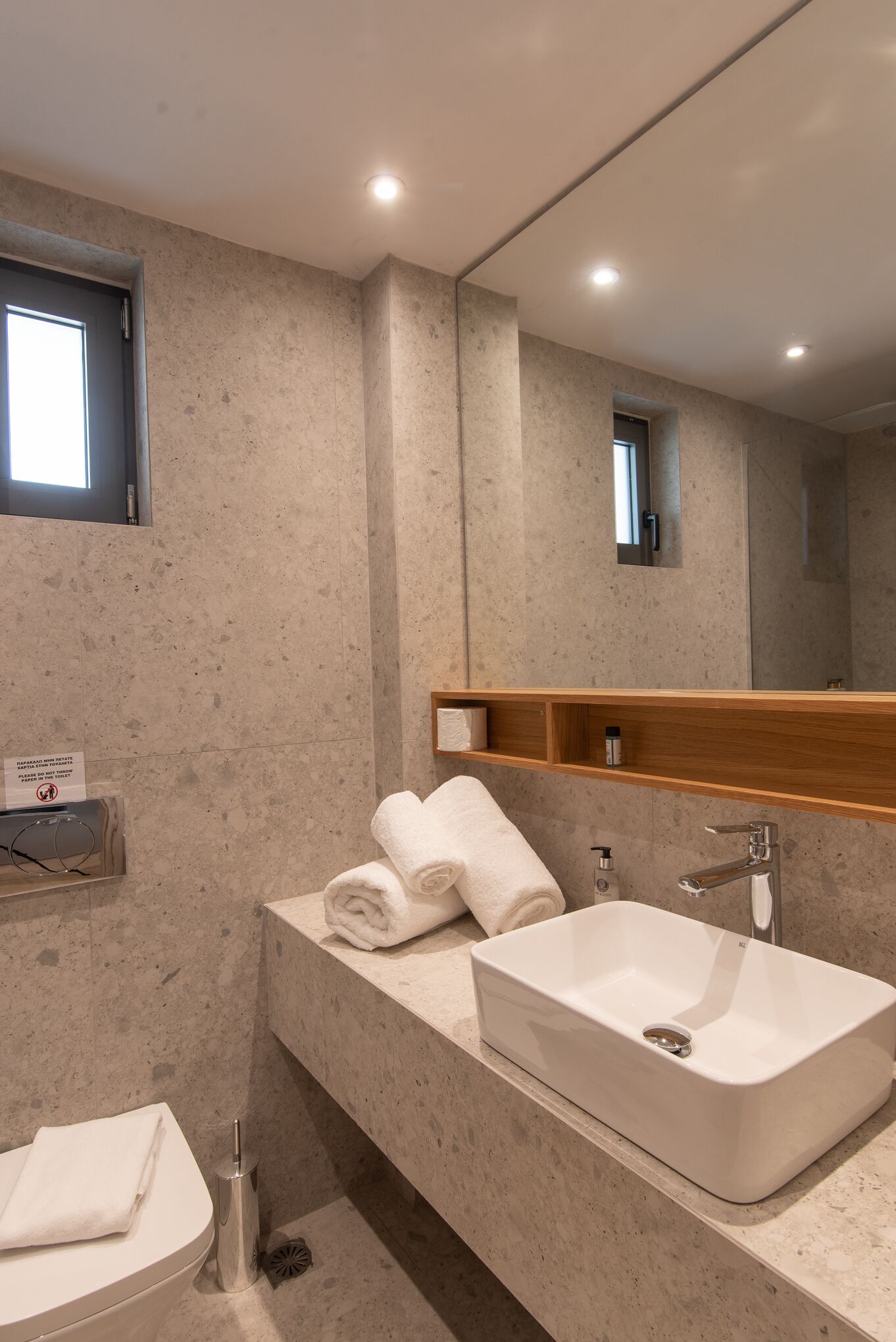 Un baño moderno con un lavamanos amplio, un espejo y un perchero para toallas.