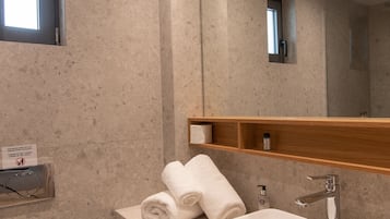 Un baño moderno con un lavamanos amplio, un espejo y un perchero para toallas.
