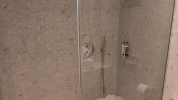 A modern bathroom with a glass-enclosed shower, a small window, and a toilet.