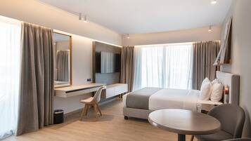 Ein modernes Hotelzimmer mit Bett, Schreibtisch, Stuhl und einem kleinen runden Tisch.