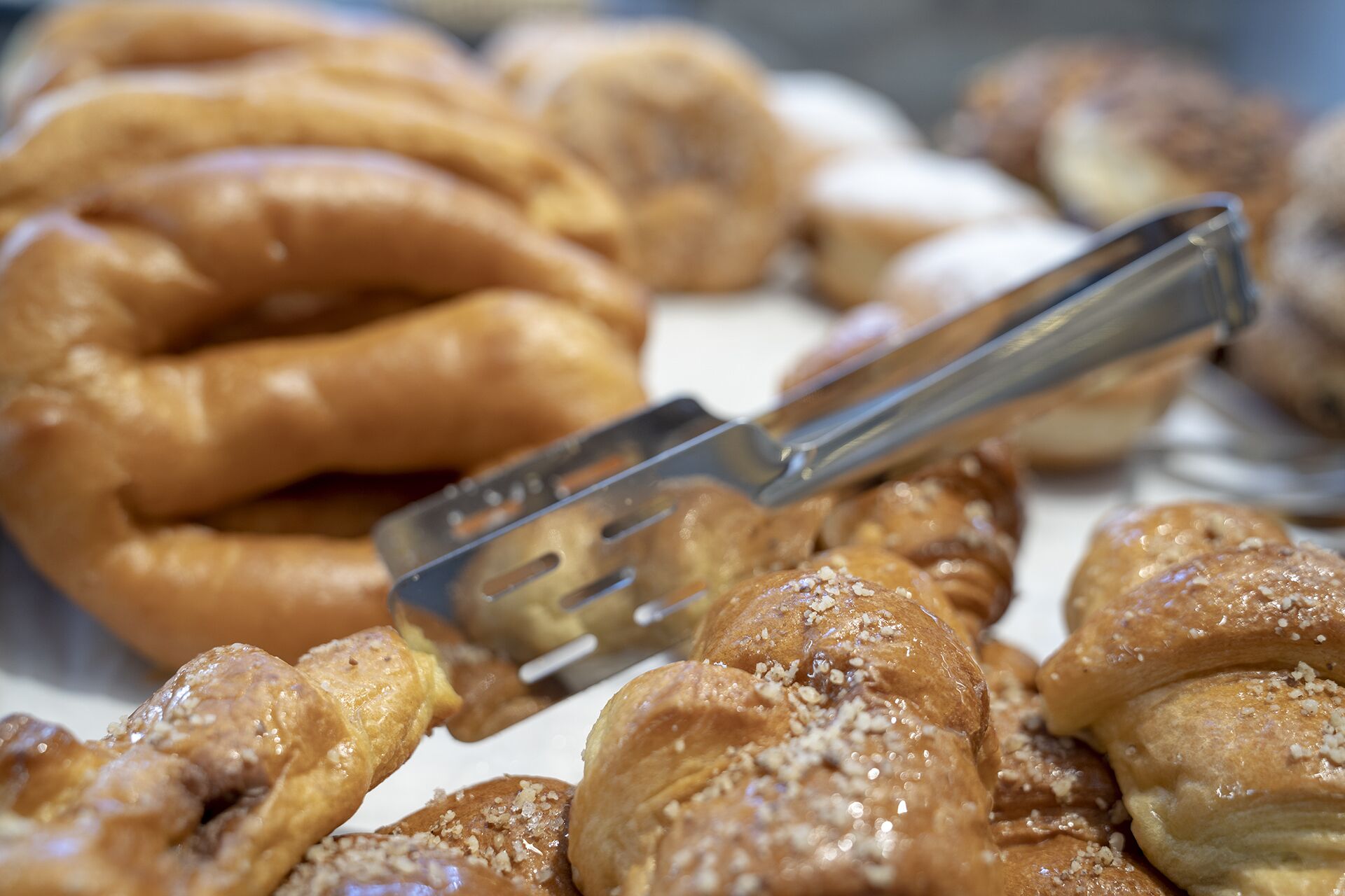 Una bandeja de pasteles con unas pinzas metálicas encima.