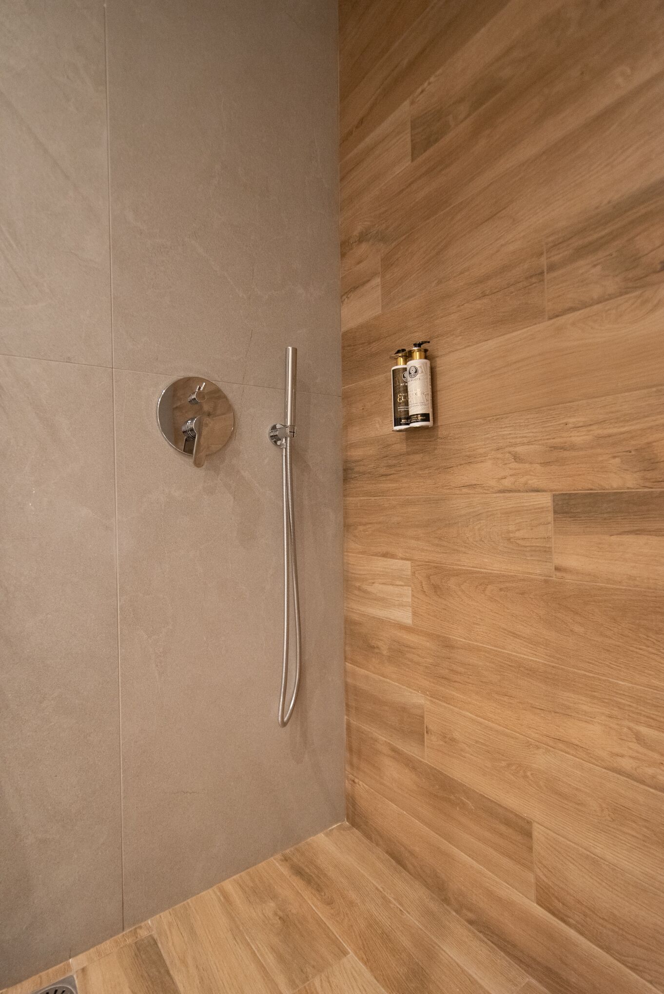 A bathroom with a shower, a toilet, and a wall-mounted bottle of shampoo.