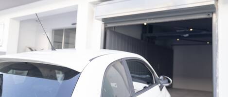 Un coche blanco estacionado frente a una puerta de garaje.