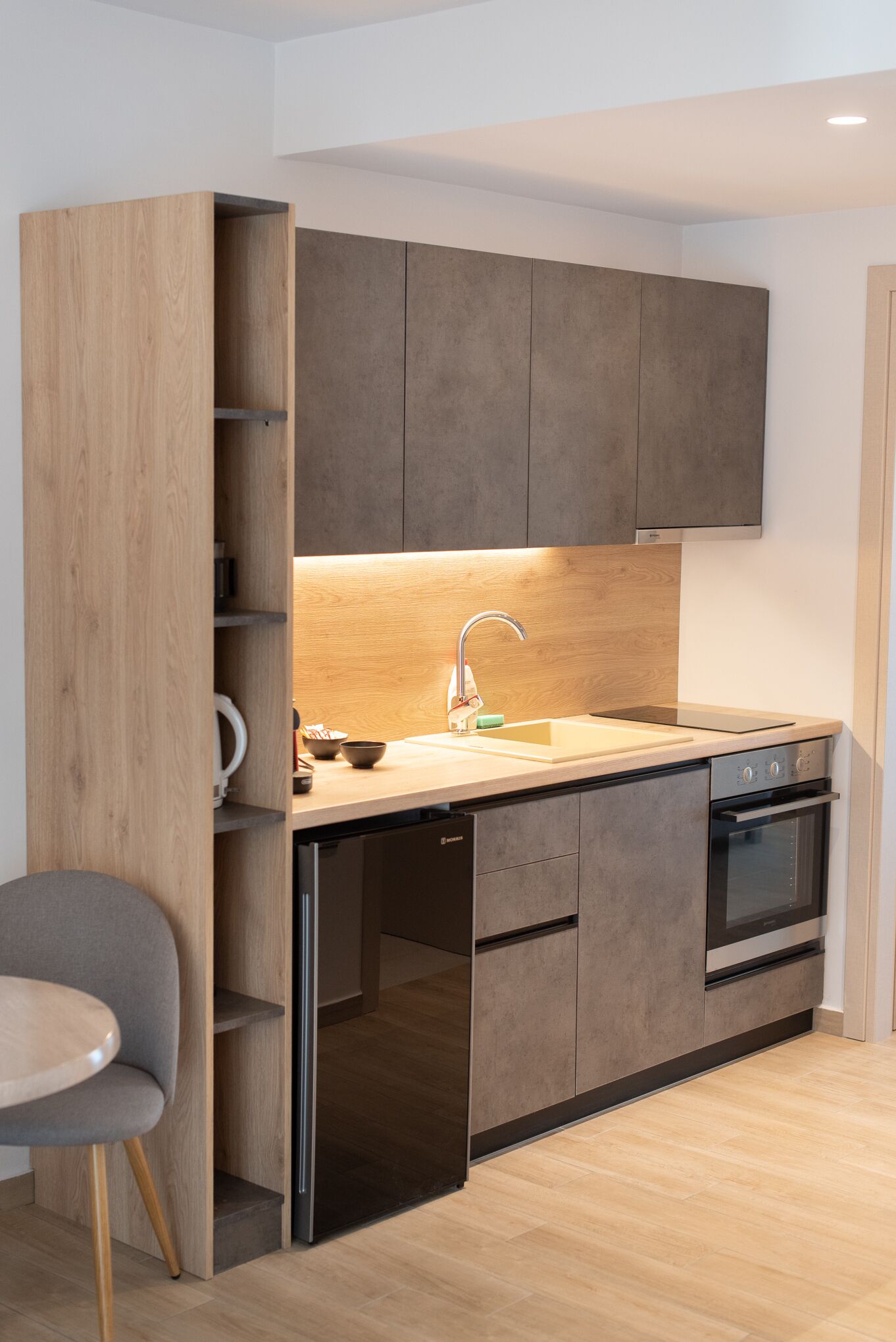 A modern kitchen with wooden cabinetry, a built-in dishwasher, and a stainless steel oven.