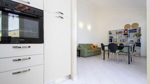A modern kitchen with a built-in oven, a dining area with a green sofa and a bookshelf. - apartment with terrace (Sant'Antioco)