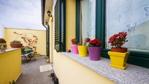 A balcony with colorful potted plants and a table with chairs. - apartment with terrace (Sant'Antioco)
