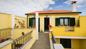 A yellow building with green shutters, a tiled roof, and a satellite dish. - apartment with terrace (Sant'Antioco)