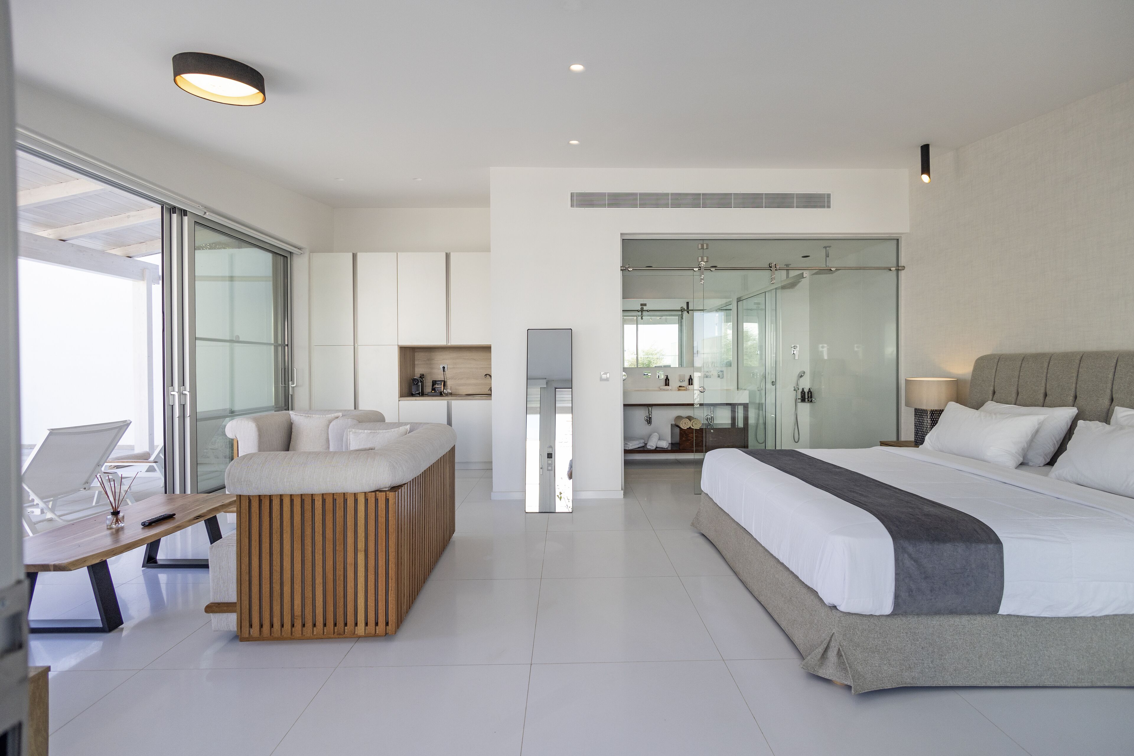 A modern hotel room with a large bed, a desk, and a seating area.