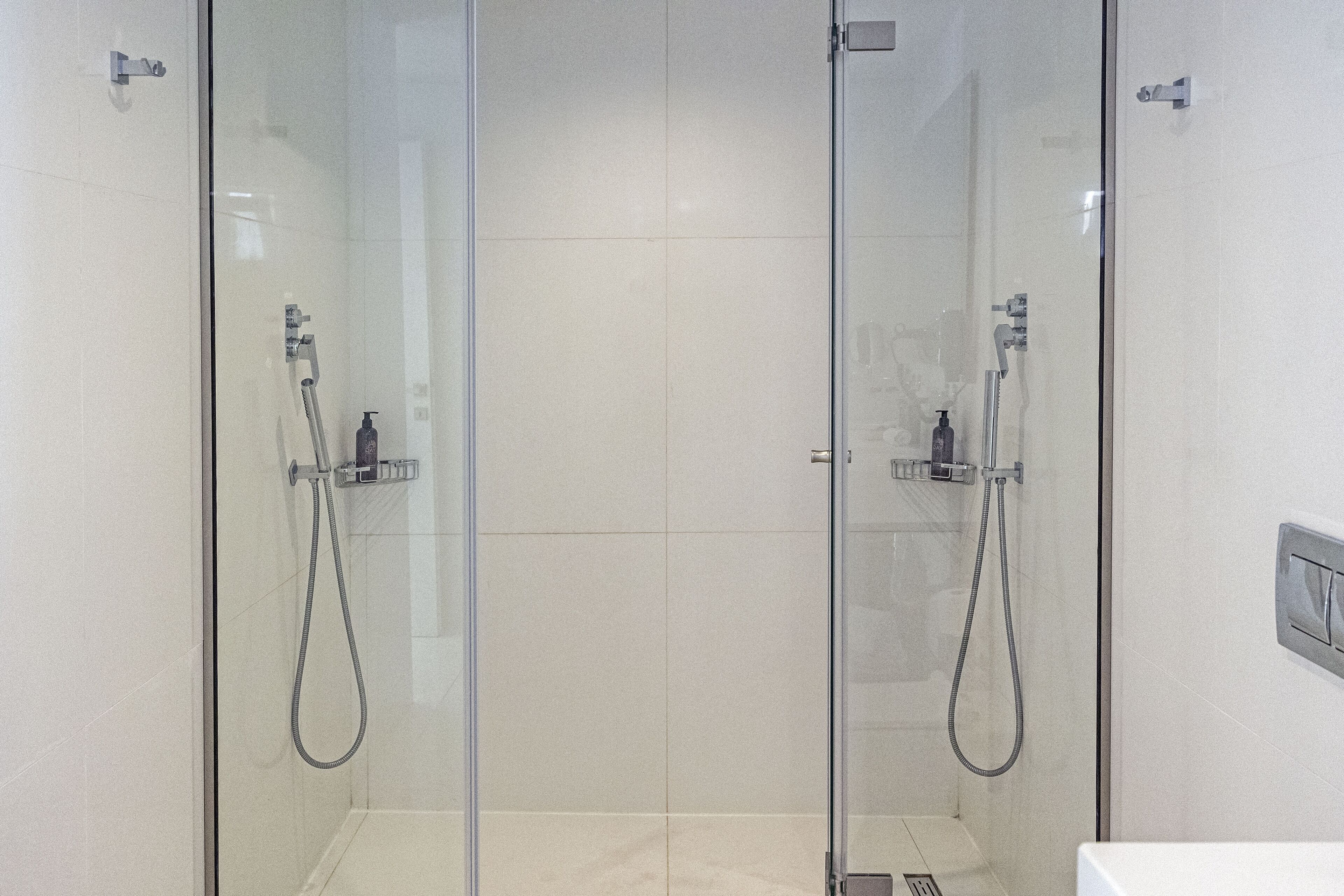 A glass-enclosed shower area with two showerheads and a control panel on the wall.