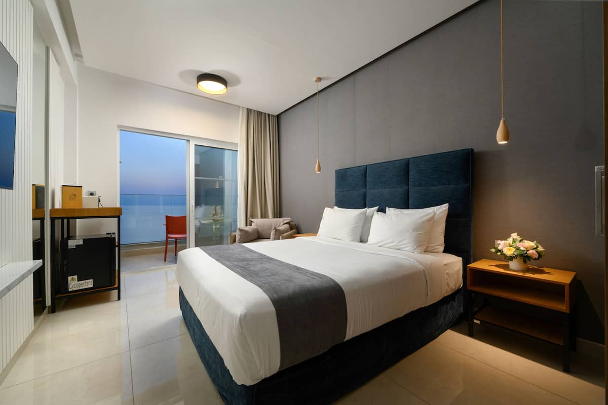 Una habitación de hotel moderna con una cama grande, un escritorio y vistas al mar.