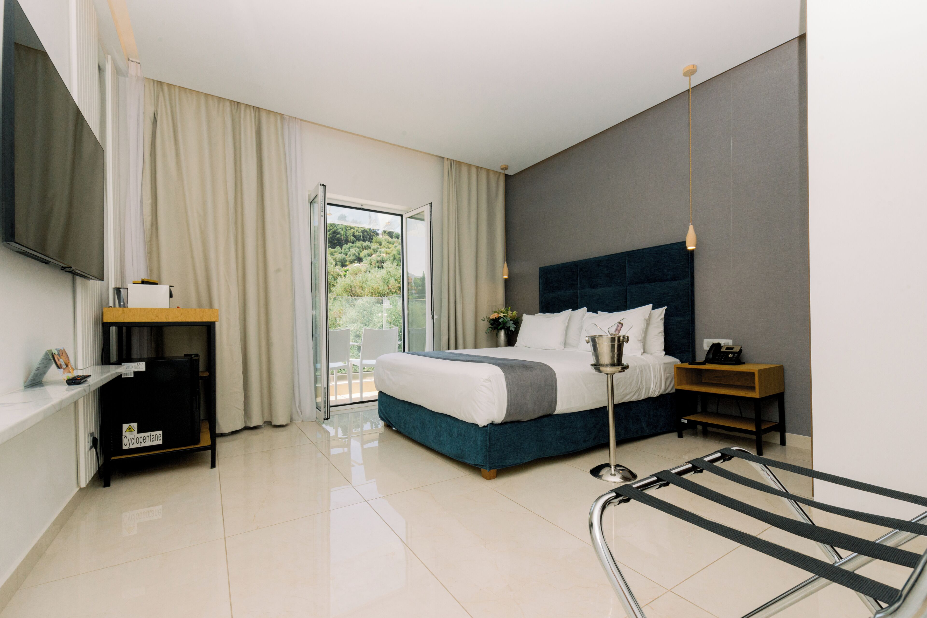 Un dormitorio moderno con cama, televisor, escritorio y vistas al exterior.