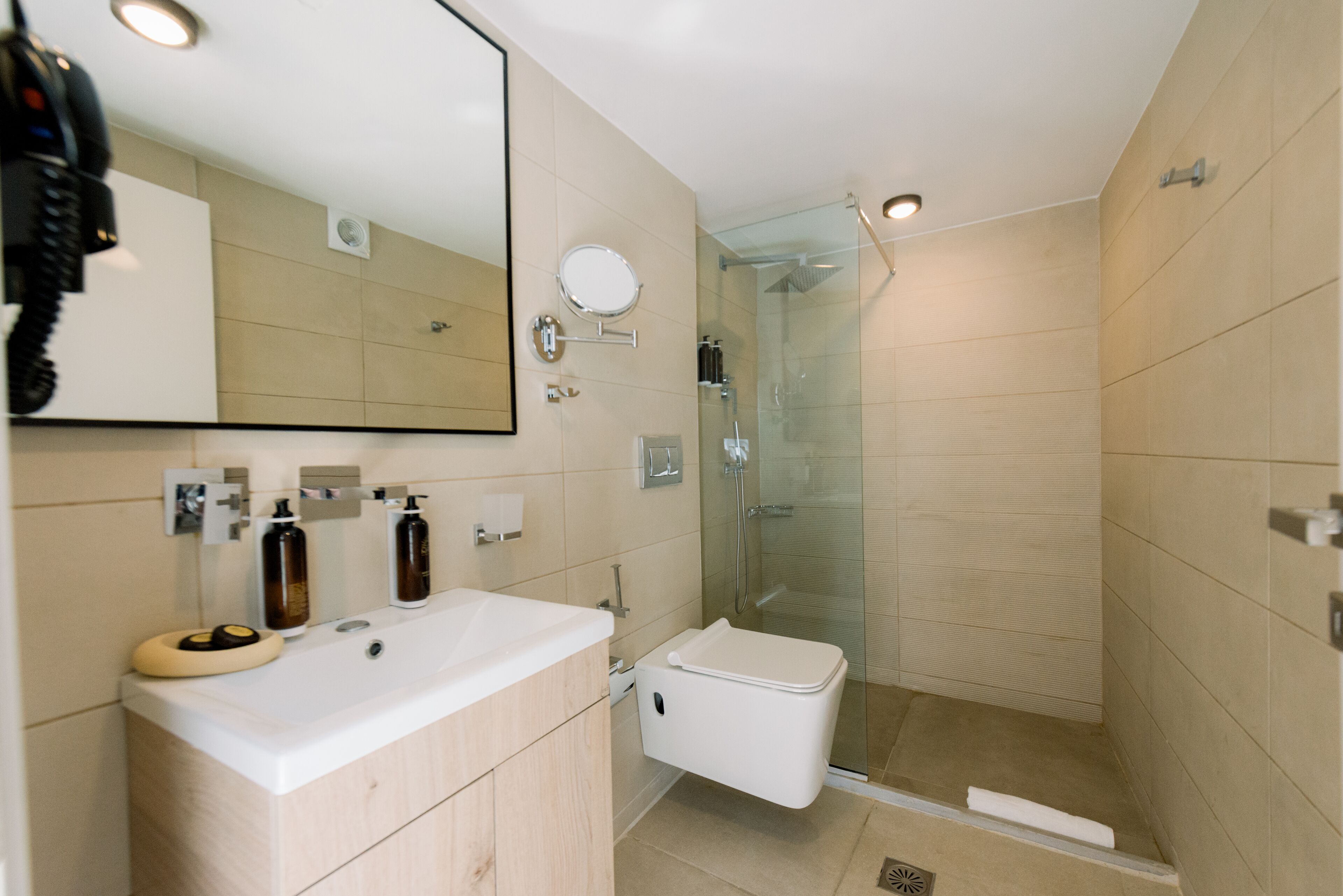 A modern bathroom with a large mirror, a sink, and a glass-enclosed shower.