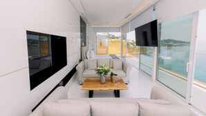 A modern living room with a sofa, a coffee table with a vase, and a TV mounted on the wall. -  Ray Hotel Corfu (Corfu)