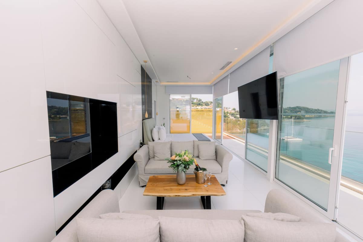 Una sala de estar moderna con un sofá, una mesa de centro con un florero y un televisor montado en la pared.