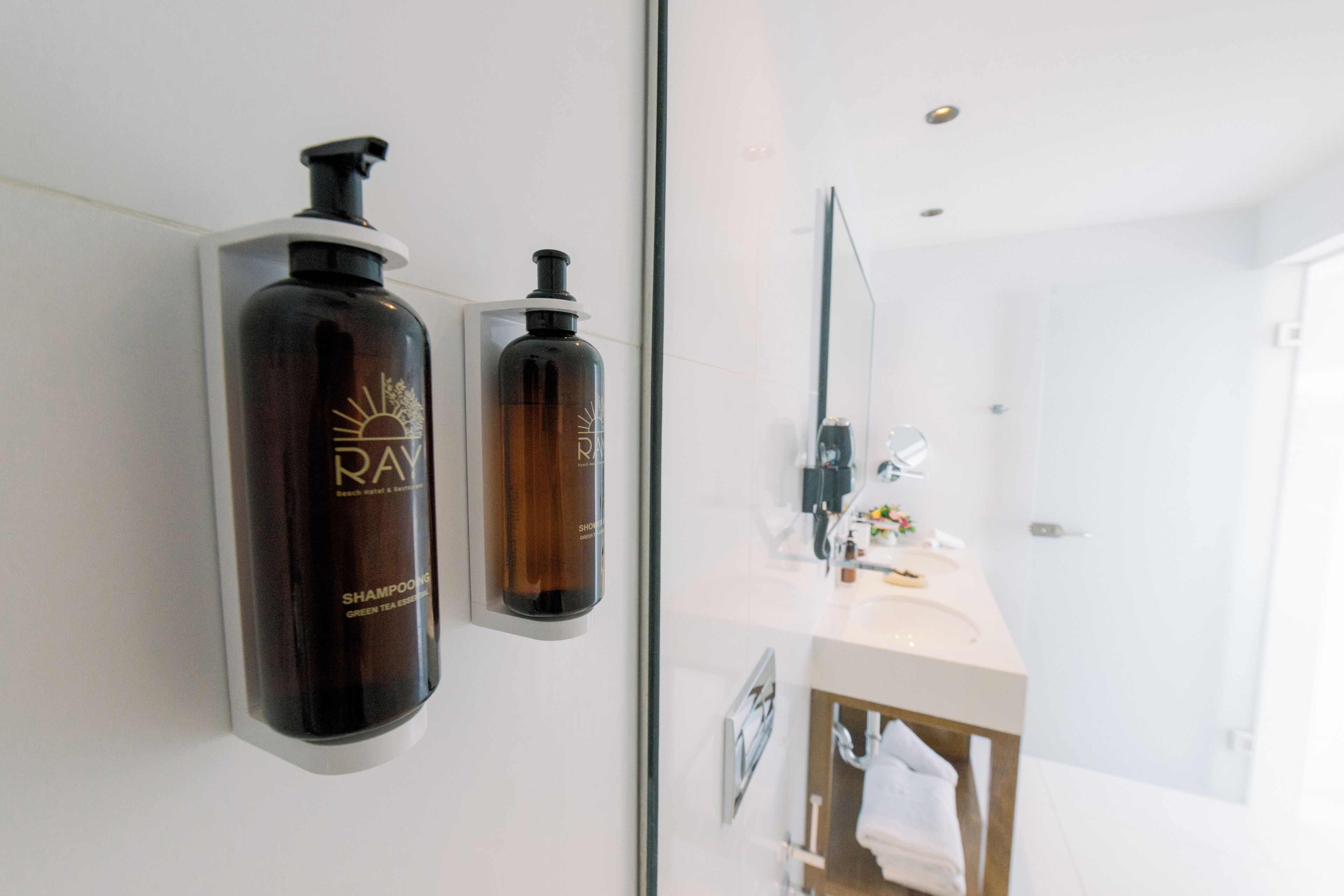 Une salle de bain avec un grand miroir, un lavabo et deux bouteilles de shampoing accrochées au mur.