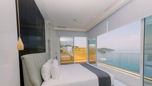 A modern bedroom with a large bed, a view of the sea, and a balcony with a wooden railing. -  Ray Hotel Corfu (Corfu)