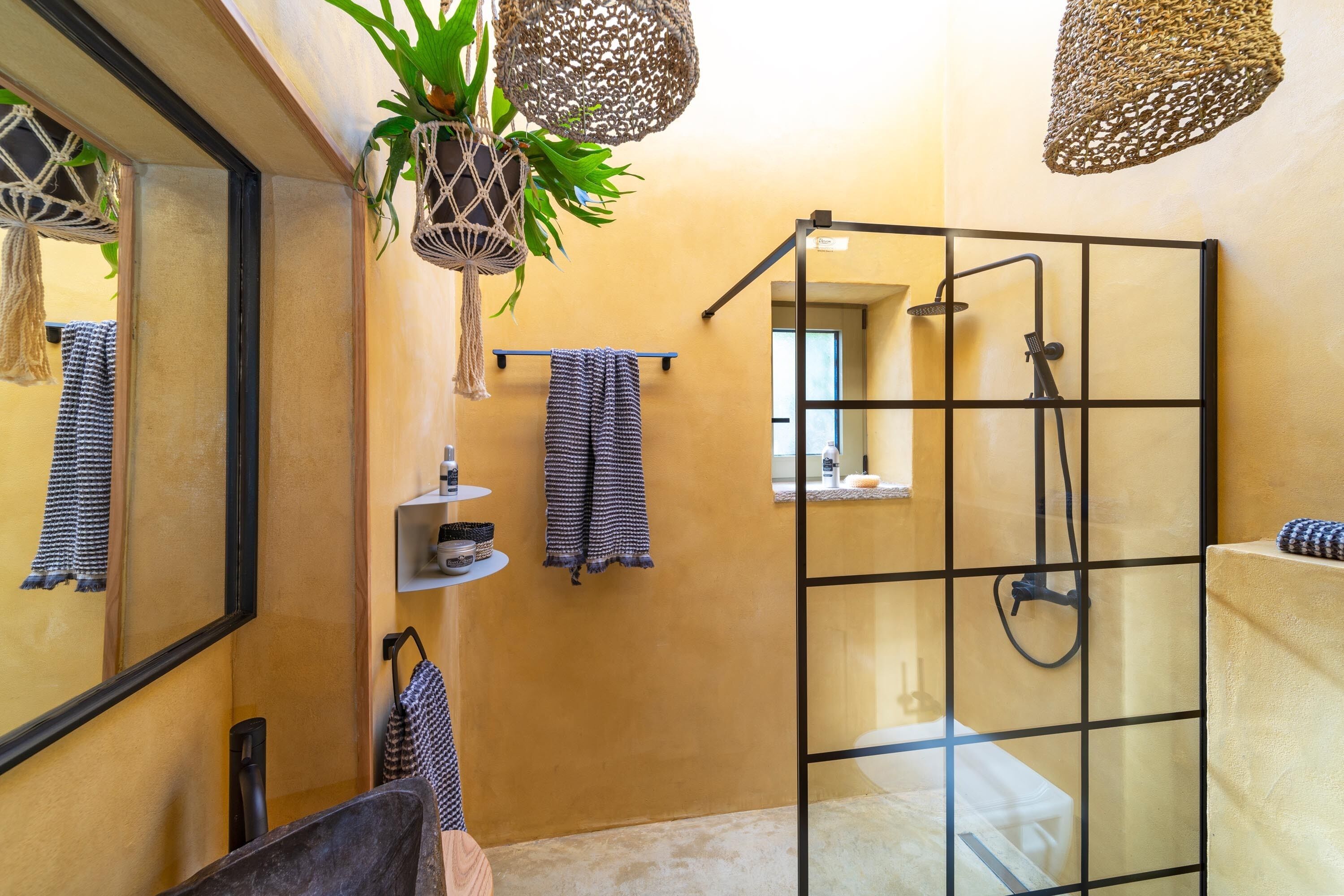 Une salle de bain moderne avec une douche à parois de verre, un grand miroir et une plante en pot.