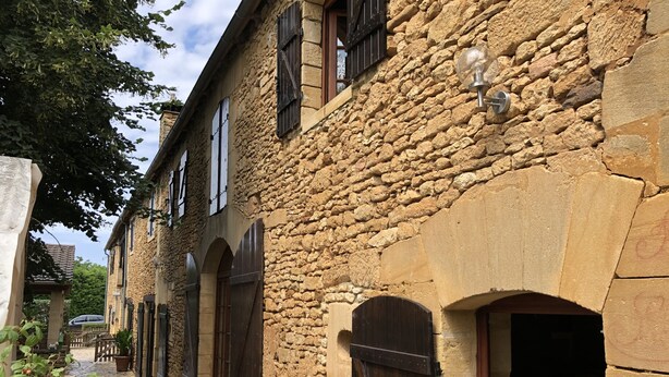 Ein Steinhaus mit Rundbogenöffnungen und einem Kopfsteinpflasterweg.