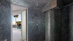 A bathroom with mosaic tile walls and a view of an outdoor swimming pool. - Villa Catalina (Benalmádena)
