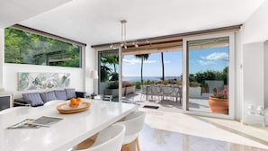 A modern kitchen with a large island, white chairs, and a view of the ocean through large sliding doors. - Villa Catalina (Benalmádena)