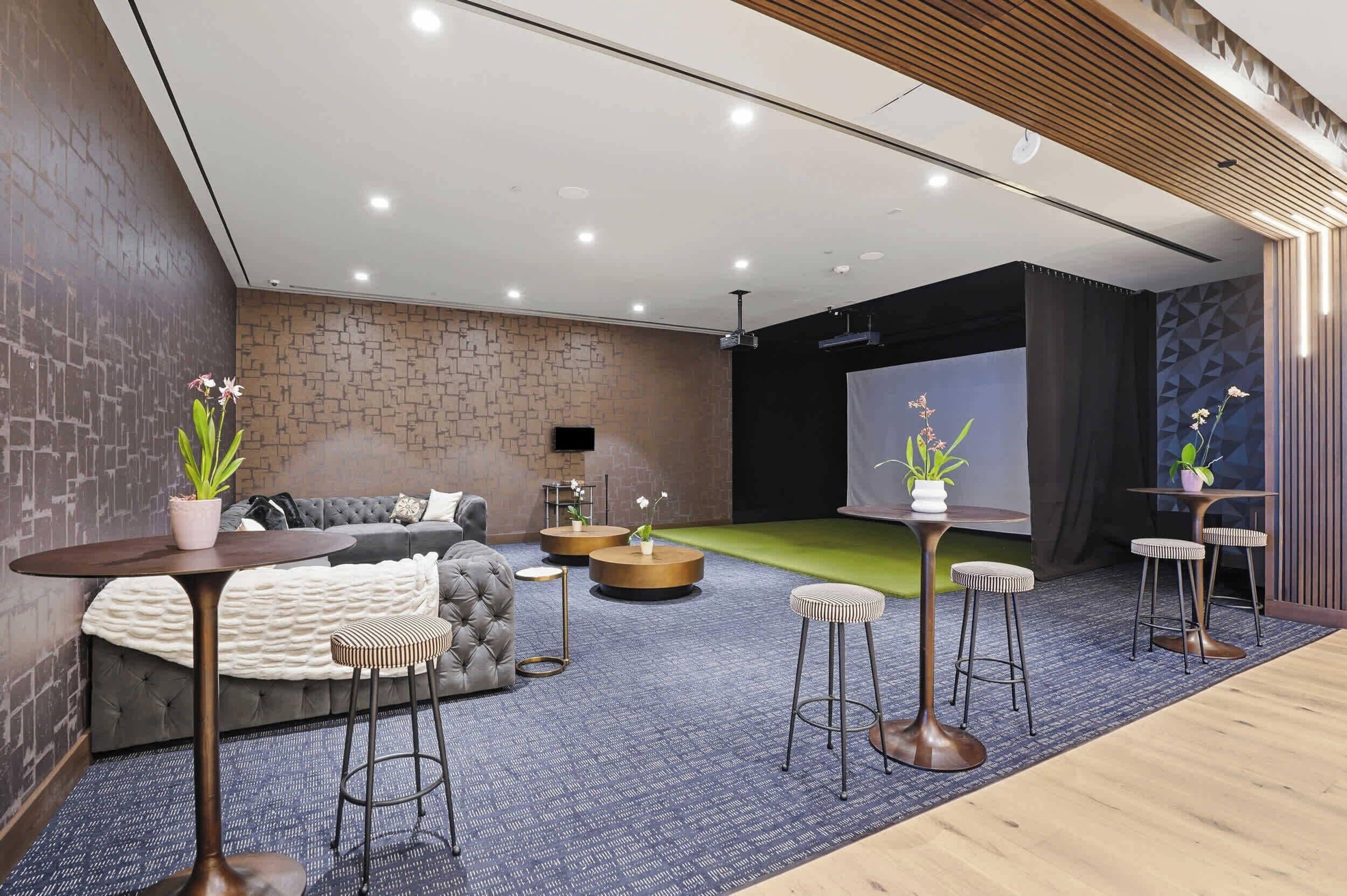 A modern living room with a grey sofa, round coffee table, and bar stools.