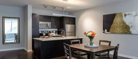A modern kitchen with dark cabinetry, stainless steel appliances, and a central island.