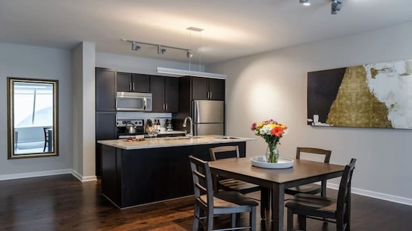 Una cocina moderna con armarios oscuros, electrodomésticos de acero inoxidable y una isla central.