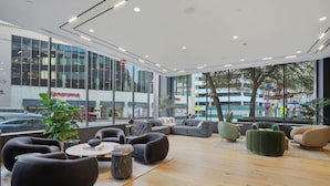 A modern interior with a seating area, large windows, and a view of the outside. - CozySuites - Remi (Dallas)