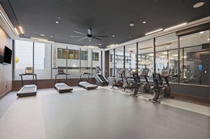 Un gimnasio moderno con cintas de correr, elípticas y bicicletas estáticas.