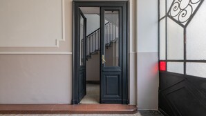Ein Gang mit einer schwarzen Tür, die zu einer Treppe führt.