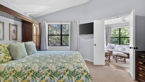A bedroom with a large bed, a wardrobe, a TV, and a view of the outdoors. - 2br/2ba Walk to pier/village area.  1/2 mile to beach (Saint Simons Island)