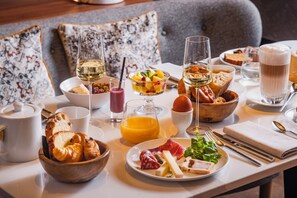 A breakfast setting with bread, fruit, cheese, and drinks on a table. - Hôtel LÉONOR the place to live By Stay Collection (Strasbourg)