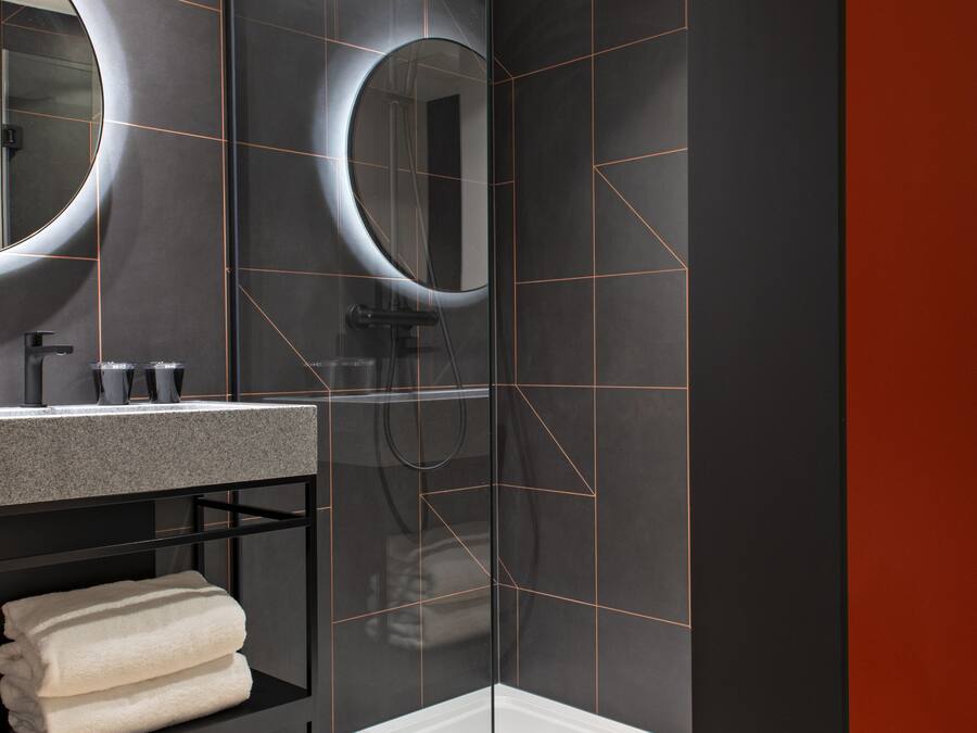 A modern bathroom with a glass shower enclosure, a vanity with a mirror, and a towel rack.
