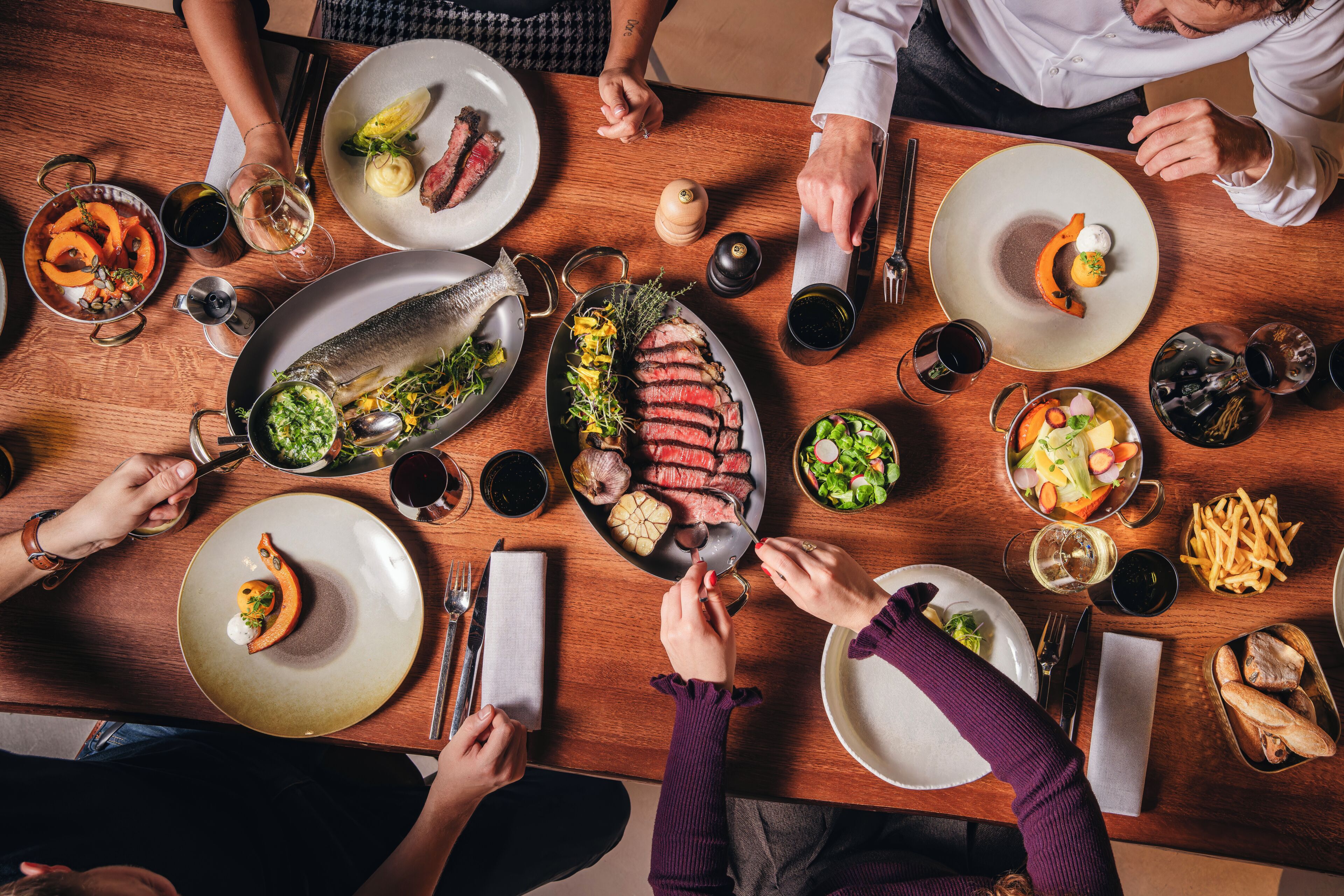 Una mesa de comedor con diferentes platos, utensilios y vasos.