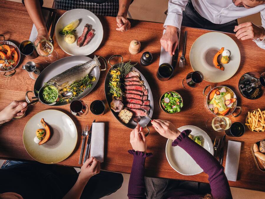 Une table à manger avec différents plats, couverts et verres.