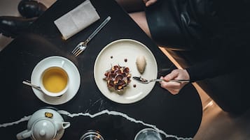 A table with a teapot, cups, a plate with dessert, and a fork.