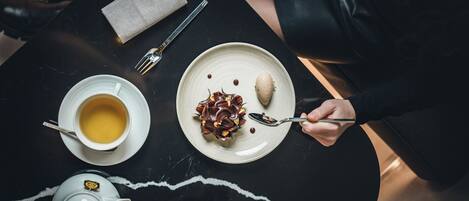 Una mesa con una tetera, tazas, un plato de postre y un tenedor.