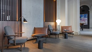 Un interno moderno con un'area salotto con divani e un tavolo, pannelli in legno e un grande quadro astratto appeso alla parete.