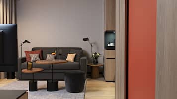 Ein modernes Wohnzimmer mit einem grauen Sofa, zwei Beistelltischen, einem Couchtisch und einem schwarzen Ottomanen.