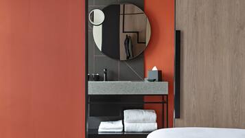 Une salle de bain moderne avec un miroir rond, un lavabo et un porte-serviettes.